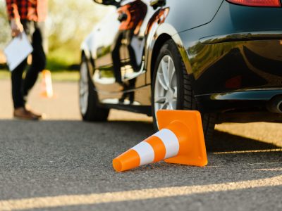 male-instructor-at-the-car-downed-traffic-cone-2021-08-28-17-17-22-utc-min